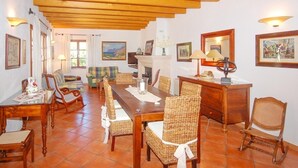 Un comedor con una larga mesa de madera, sillas de mimbre y una chimenea.