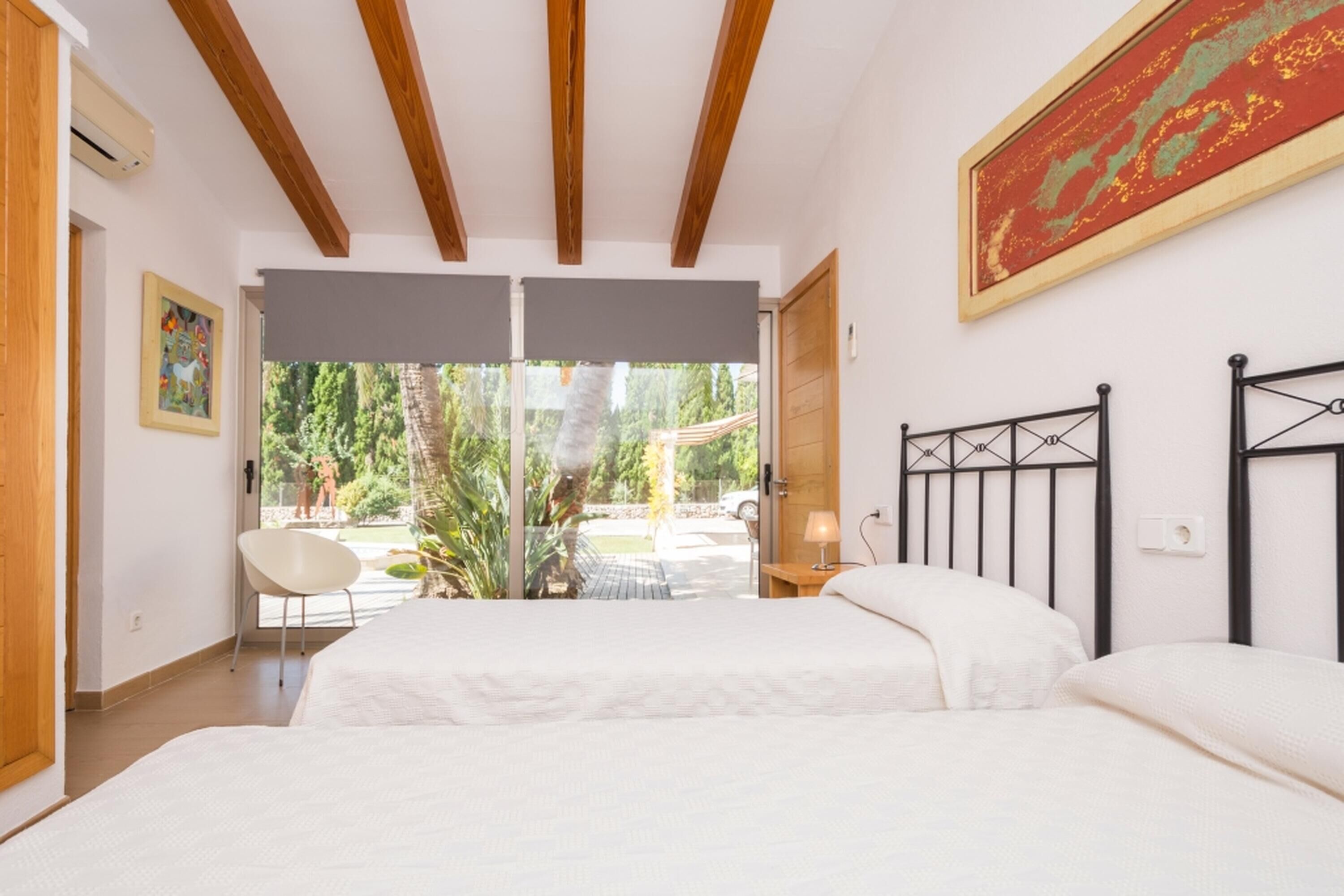 Un dormitorio con una cama grande, una silla, una ventana y un cuadro en la pared.
