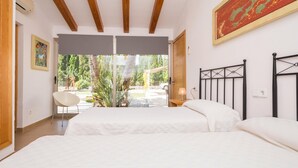Ein Schlafzimmer mit einem großen Bett, einem Sessel, einem Fenster und einem Bild an der Wand.