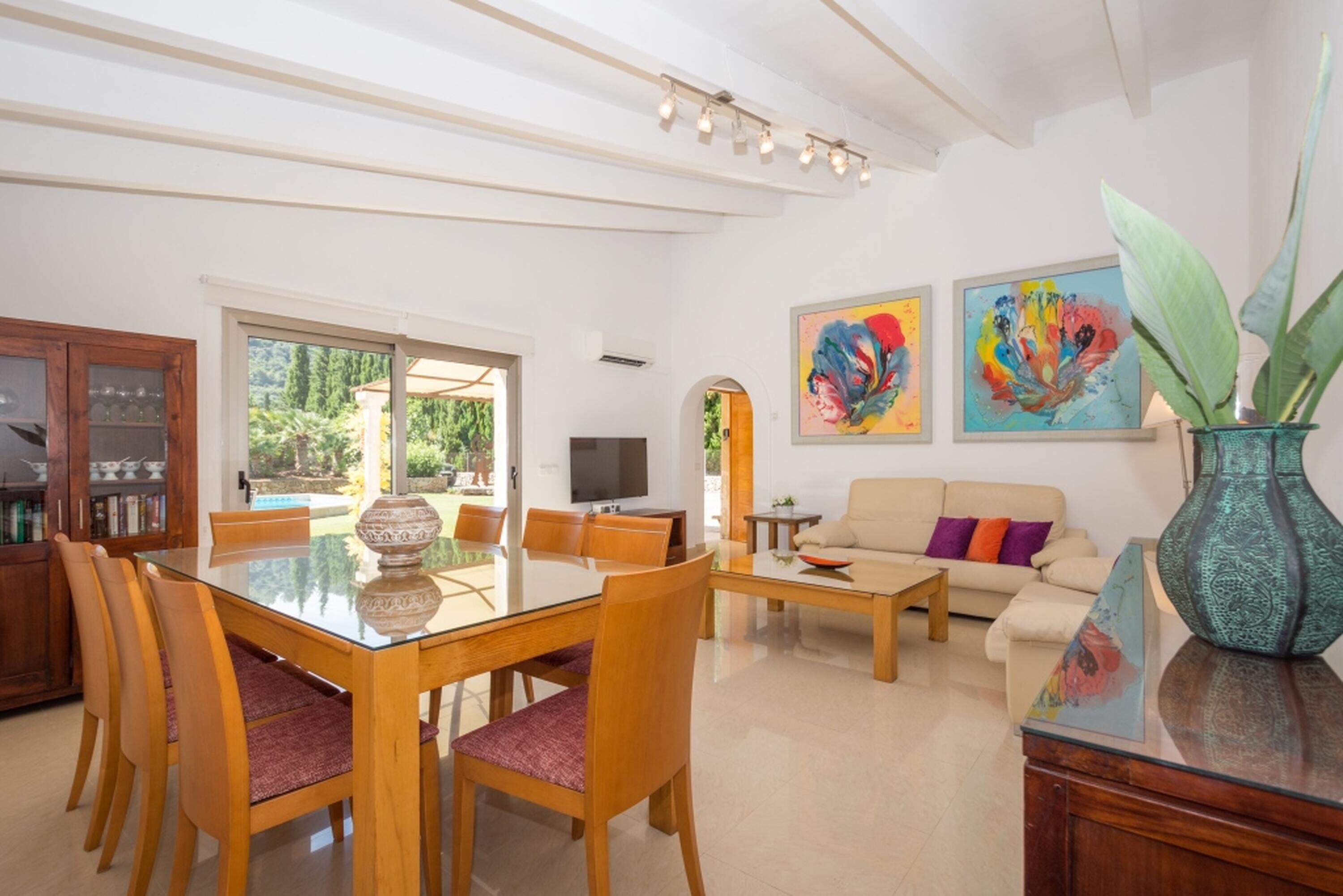 Un salón amplio con comedor, un sofá y dos cuadros abstractos en la pared.