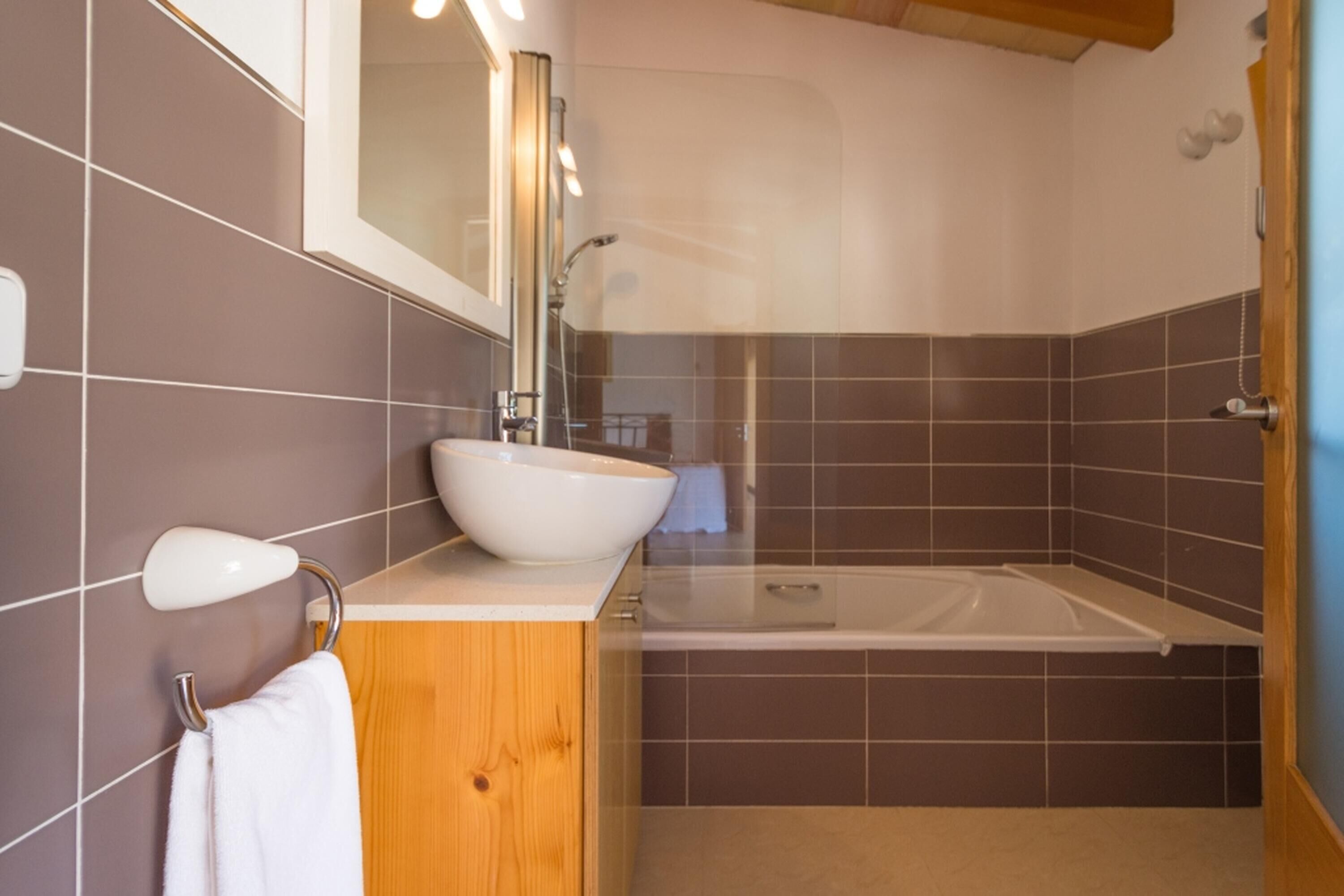 Une salle de bain moderne avec un lavabo, un miroir et une baignoire.