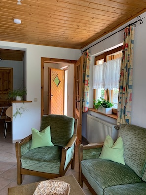 Una stanza accogliente con mobili in legno, un termosifone e una finestra con tende a motivi decorativi.