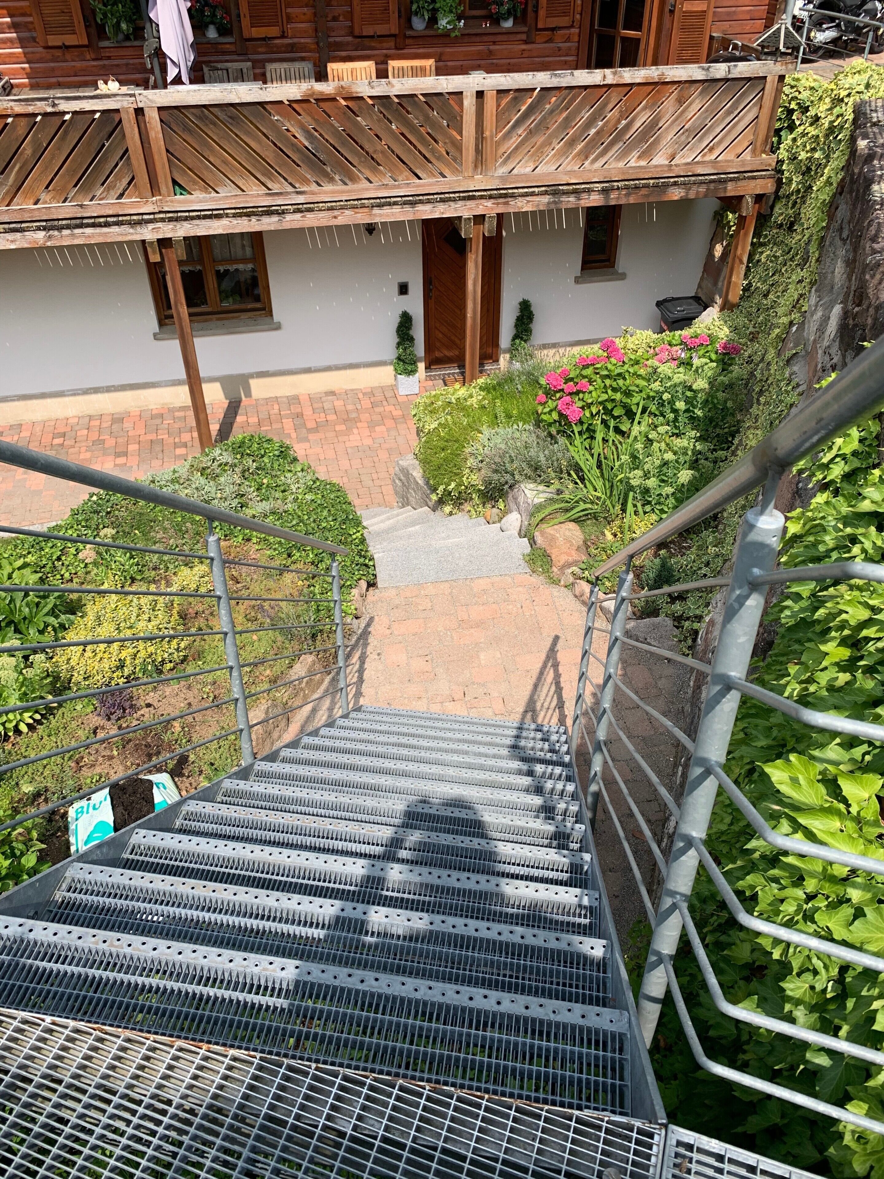 Uma escada de madeira que leva a uma varanda com guarda-corpo de metal.