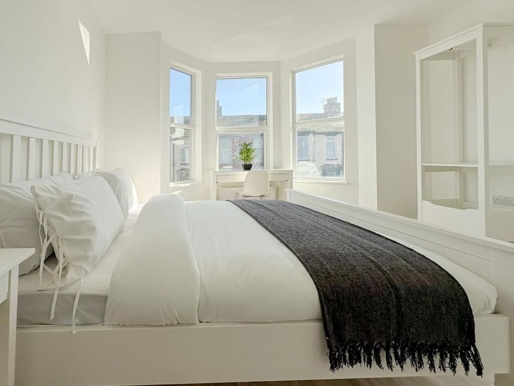 A bedroom with a bed, a bedside table, a window, and a view of the city.