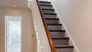 A staircase with wooden steps and a wooden handrail, leading to a door at the top. - Nelson Road - 3 Bed Terrace in Yarmouth (Great Yarmouth)