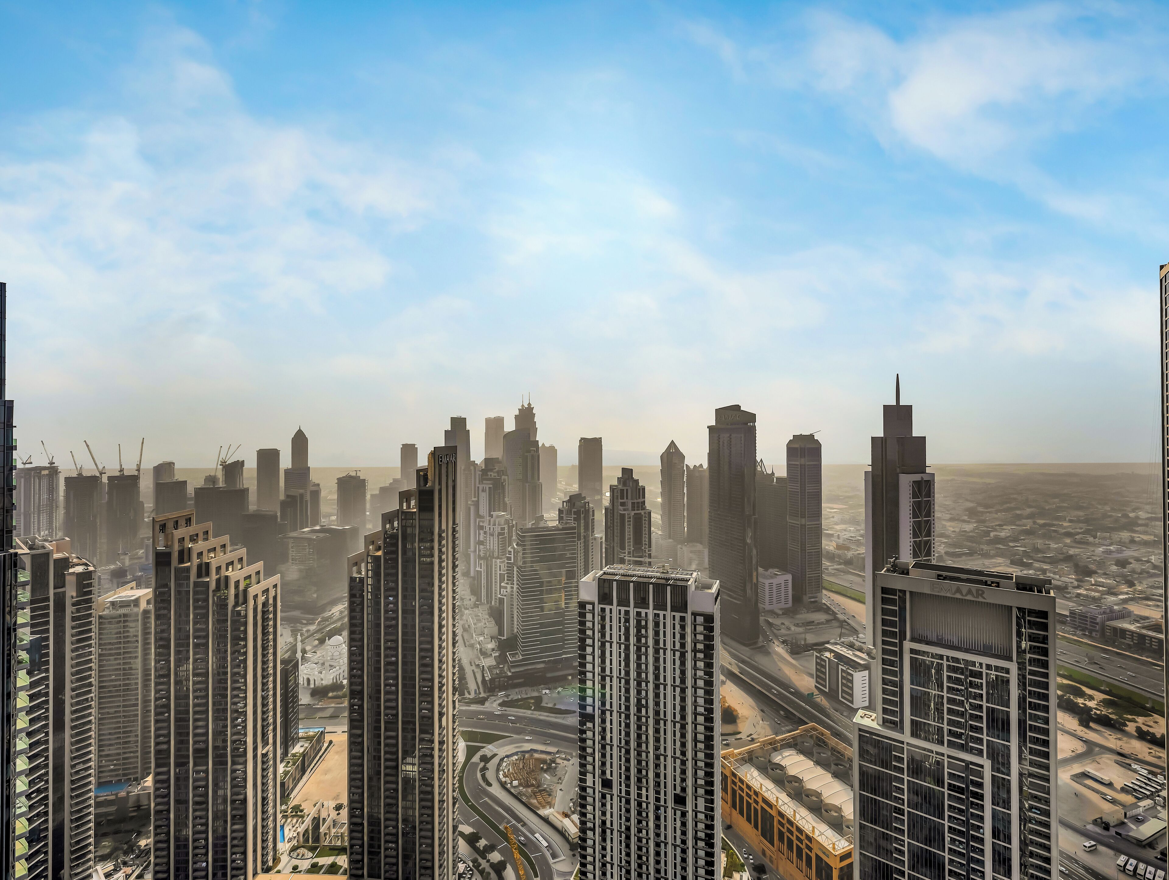 Un paysage urbain dominé par de hauts gratte-ciel modernes, une autoroute animée et un ciel dégagé.