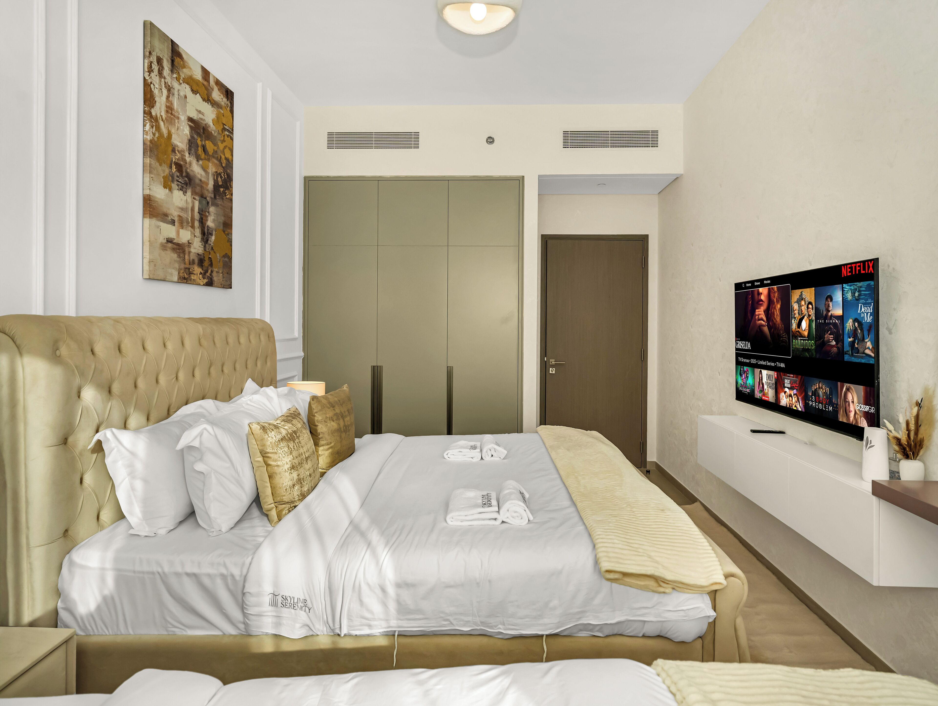A hotel room with a bed, a television displaying a Netflix interface, and a painting on the wall.