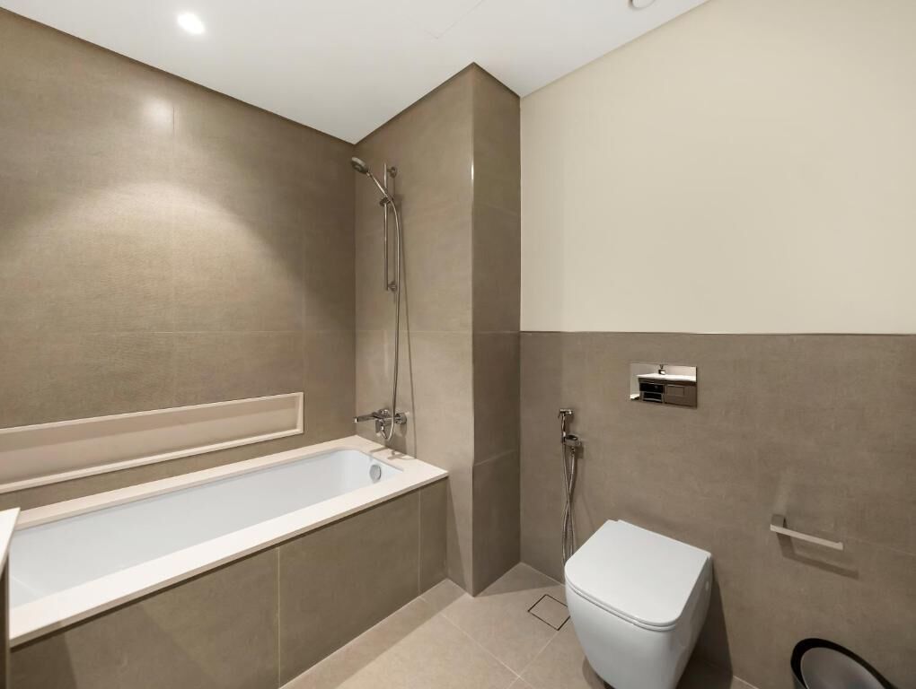 A modern bathroom with a bathtub, shower, and toilet.