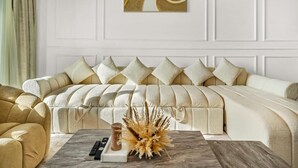 Un salon avec un canapé beige, une table basse sur laquelle se trouve un vase, et un tableau accroché au mur.