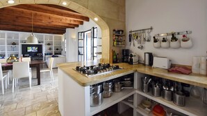 Een moderne keuken met een centraal eiland, ingebouwde opbergruimte en een eethoek met witte stoelen.