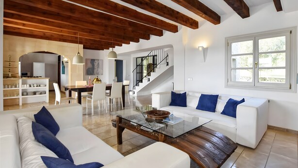 Een moderne woonkamer met een witte bank, een glazen salontafel en een trap naar een hoger niveau.