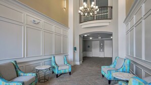 Um hall amplo com teto alto, um candelabro e vista para uma varanda.