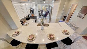 Uma mesa de jantar redonda com seis cadeiras, um vaso com flores e pratos com restos de comida.