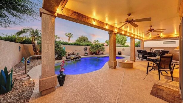 Um pátio externo com piscina, área de estar e ventiladores de teto.