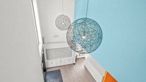 Een modern interieur met een trap, een wit kastje en twee bolvormige hanglampen.