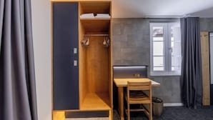 Una habitación con un armario de madera, un escritorio con una silla y una ventana con cortinas.