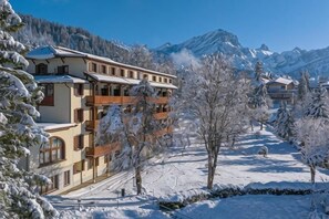 A multi-story hotel with balconies, surrounded by snow-covered trees and mountains. - Villars Lodge (Ollon)