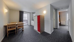 Una habitación moderna y luminosa con una mesa de comedor y sillas, un armario rojo y un ventanal que proporciona luz natural.