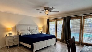 Una camera da letto con un letto, comodini, una ventola a soffitto e una finestra con tende.