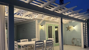Portico esterno coperto con tavolo e sedie, una porta e una decorazione a stella marina.
