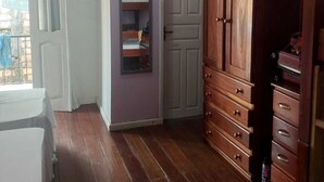 A room with wooden flooring, a white door, a wooden wardrobe, and a small shelf unit. - Casa mobiliada (Marituba)
