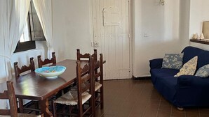 Un coin repas avec une table et des chaises en bois, un canapé bleu et une porte blanche.