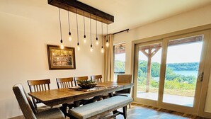 A dining area with a wooden table, chairs, and benches. There is a hanging light fixture above the table. A framed picture hangs on the wall. - Gated Lake Ranch, Private Dock & 3.5 Acres, Fire pit & Pet Friendly (Palo Pinto)
