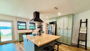 A modern kitchen with a central island, built-in appliances, and a view to the outdoors. - Gated Lake Ranch, Private Dock & 3.5 Acres, Fire pit & Pet Friendly (Palo Pinto)