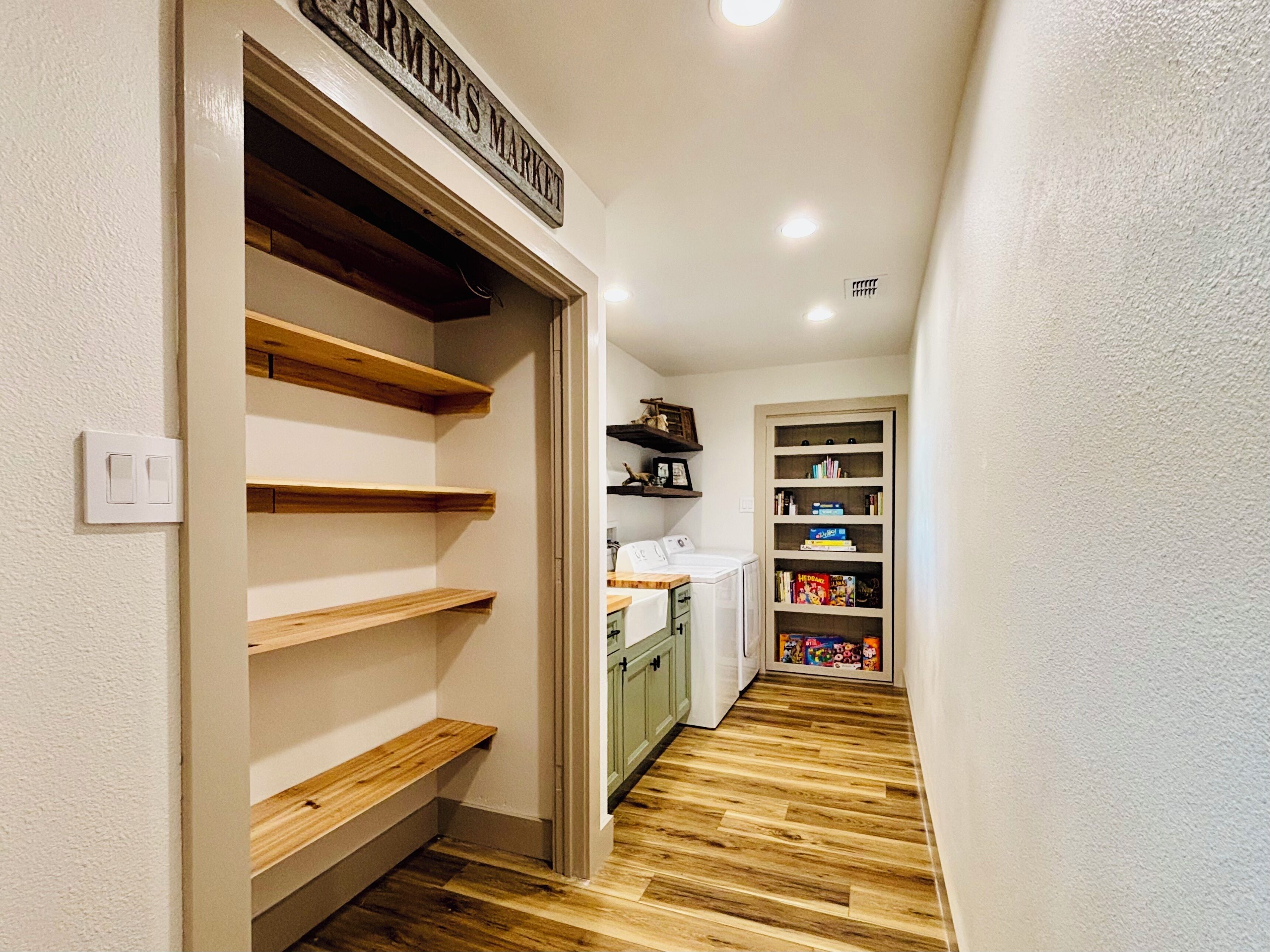 Un couloir étroit avec des étagères en bois et un espace dédié à la buanderie.
