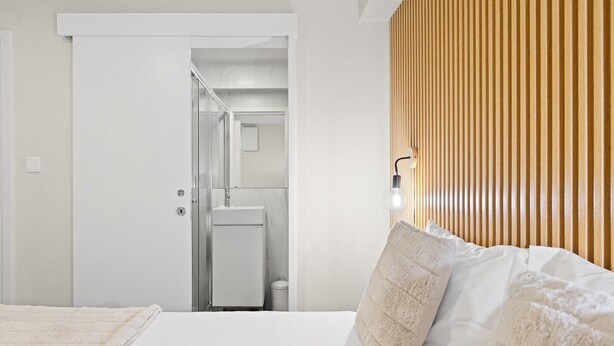 Ein Hotelzimmer mit einem Bett, einer Wand aus Holzlatten und einem durch eine offene Tür einsehbaren Badezimmer.