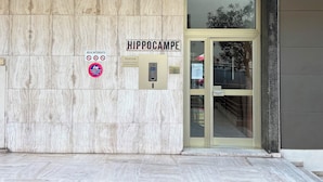 Entrada de un edificio con fachada de mármol, un letrero de recepción y un letrero de estacionamiento.