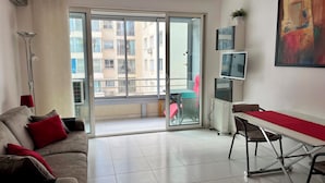 Una sala de estar moderna con un sofá, una mesa de comedor y un puerta corrediza de vidrio que da a un balcón.