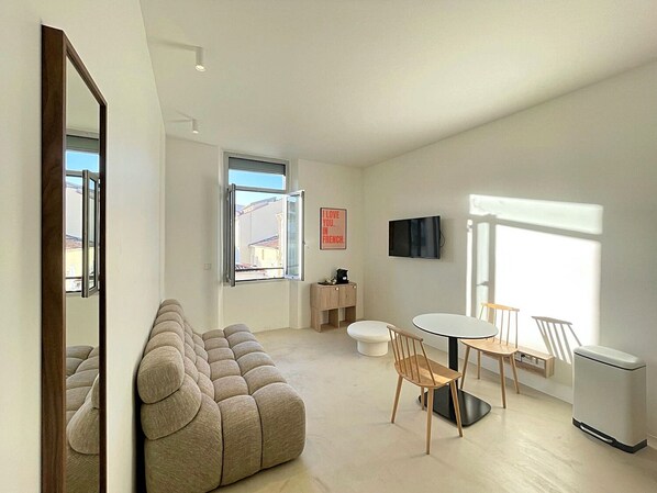 Ein modernes Wohnzimmer mit einer Couch, einem Esstisch mit Stühlen, einem Fernseher und einem Fenster mit Blick.
