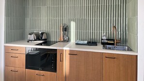 A modern kitchen with a built-in dishwasher, a coffee machine, and a kettle on the countertop. - Viva Riviera Design and Sunny Commandant André (Cannes)