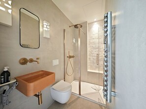 Ein modernes Badezimmer mit einem Holzwaschtisch, einer weißen Toilette, einer Duschkabine aus Glas und einem großen Spiegel.