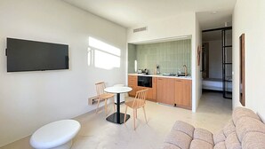 A modern living room with a sofa, a dining table with chairs, a kitchen area with a sink and stove, and a TV mounted on the wall. - Viva Riviera Design and Sunny Commandant André (Cannes)