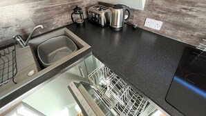 Eine moderne Küche mit einer Spüle aus Edelstahl, einer Kaffeemaschine, einem Toaster und einem Geschirrspüler.