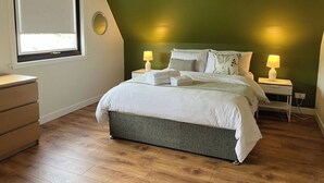 Ein Schlafzimmer mit einem Bett, Nachttischlampen, einem Schminktisch und einem Fenster.