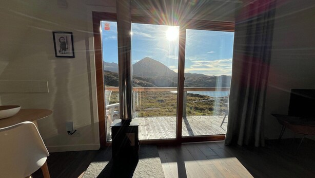 Ein Zimmer mit einer großen Schiebetür, die auf einen Balkon mit Blick auf die Berge führt.