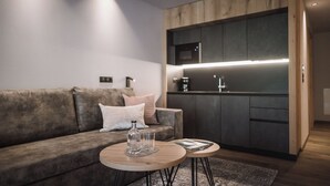 Una sala moderna con un sofá, dos mesitas redondas y una cocina integrada.