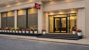 A hotel entrance with a sign, large windows, and potted plants. - 99 Hotel Apple Park (New Delhi)