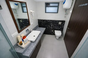 Un bagno con un lavandino bianco, una schiena di marmo nero, uno specchio, un asciugacapelli e un water.