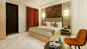 A hotel room with a bed, bedside table, chair, and a wall-mounted phone. - 99 Hotel Apple Park (New Delhi)