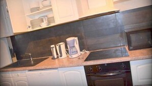 A kitchen with white cabinets, a countertop, a coffee maker, and a microwave.