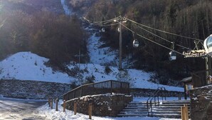 Une zone montagneuse enneigée, avec un télésiège, des marches en pierre et une clôture en bois.