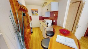 Une cuisine de taille réduite, dotée de meubles en bois, d’un four à micro-ondes et d’un évier.