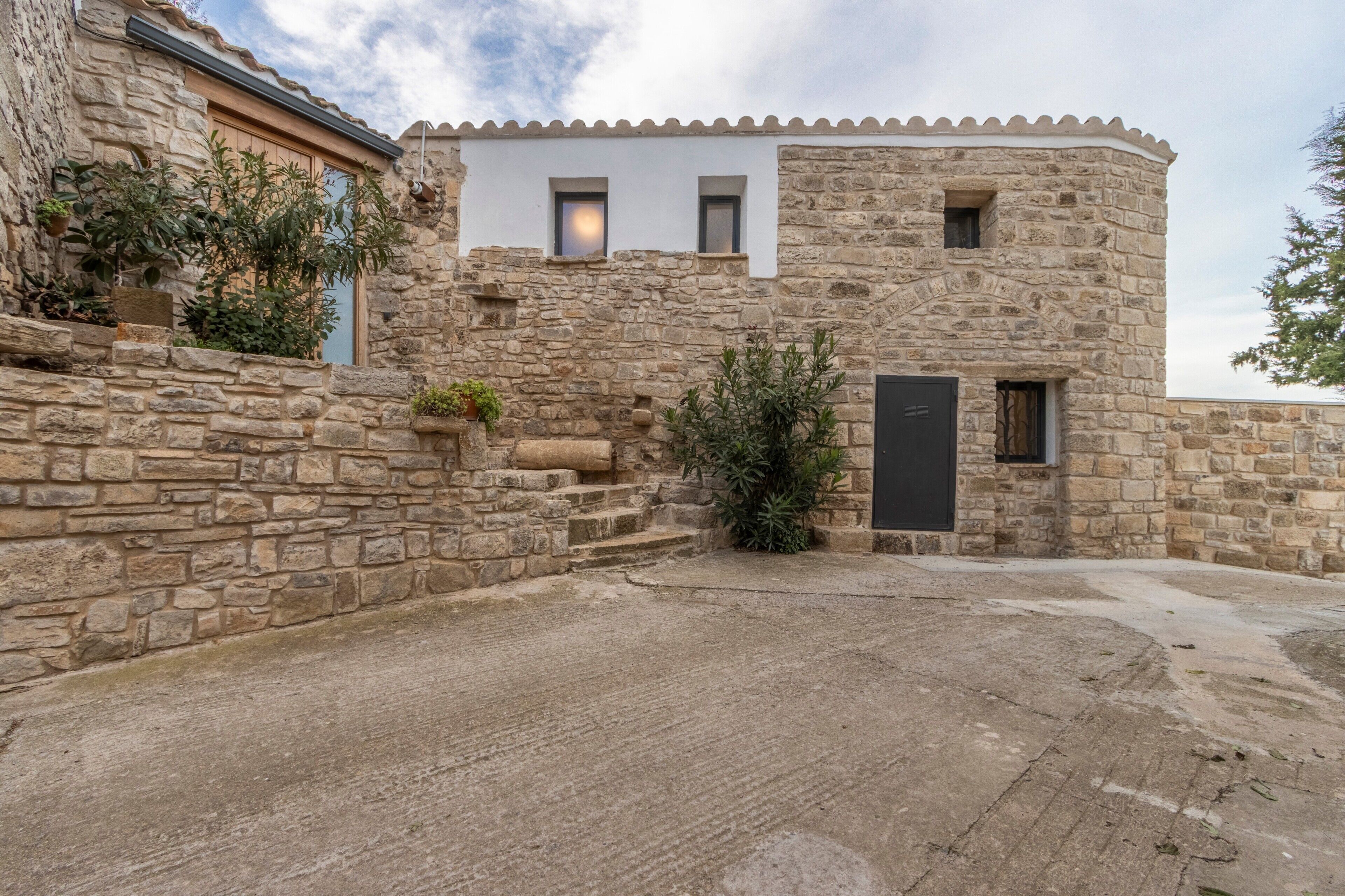 A stone building with a courtyard, a small window, and a door.