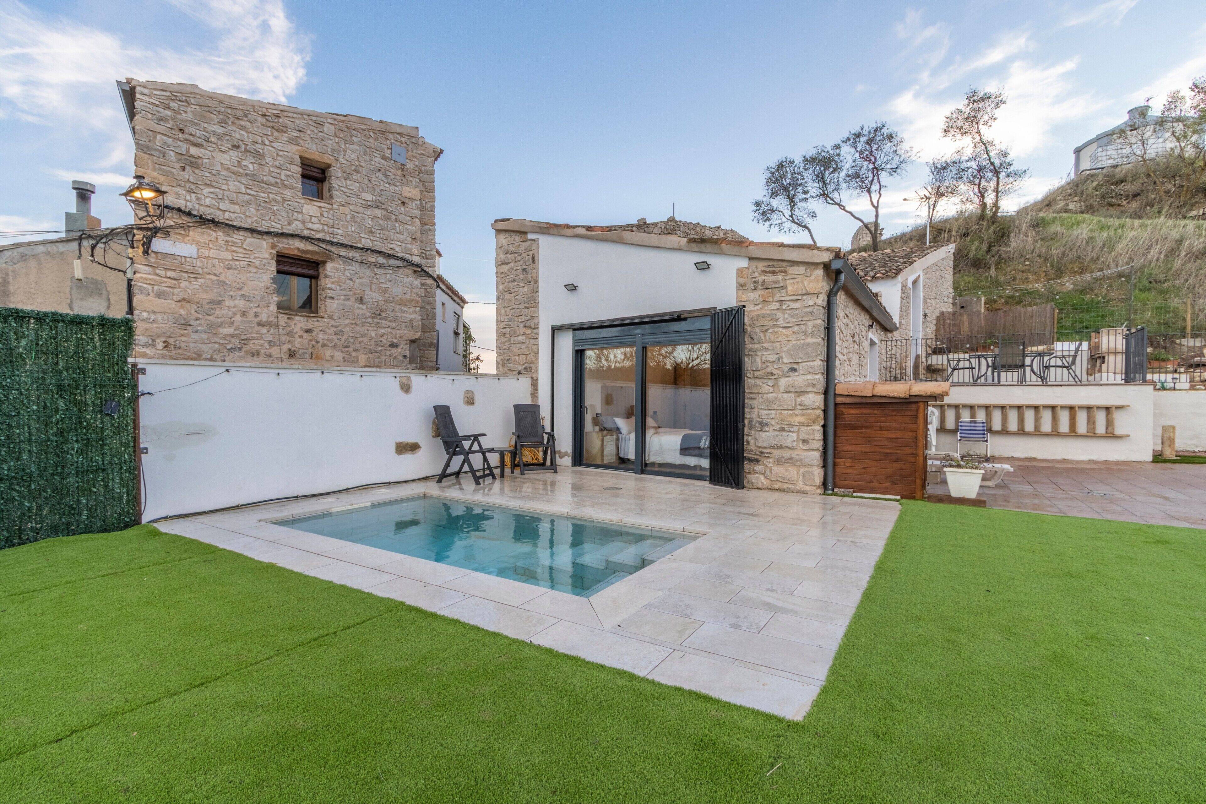 Una casa moderna con piscina, muros de piedra y un patio.