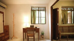 A room with a desk, chair, and a small table with a plant. There is a window with curtains and a door leading to another room. - Baannoi Retreat and Stay Chiang Mai (Chiang Mai)