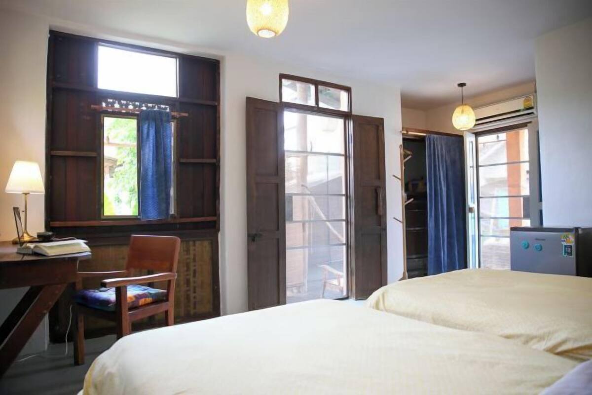 Une chambre comprenant un lit, un bureau avec une chaise, une fenêtre avec des rideaux et un appareil de climatisation.